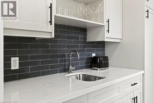 White shaker cabinetry with matte black hardware, a dark subway tile backsplash, a stainless steel undermount sink, and a chrome faucet - 128 Canada Street, Hamilton, ON - Indoor Photo Showing Kitchen