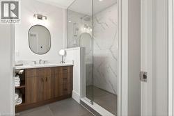 Bathroom featuring a glass-enclosed shower with white marble-style tiled walls and a rain showerhead - 