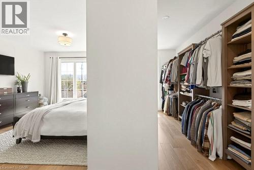 Bedroom with wood-finish flooring and a walk-in closet featuring custom wood shelving and hanging rods - 128 Canada Street, Hamilton, ON - Indoor