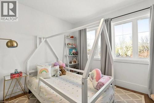 Bright room featuring two large windows, white walls, and wood-finish flooring - 128 Canada Street, Hamilton, ON - Indoor Photo Showing Bedroom