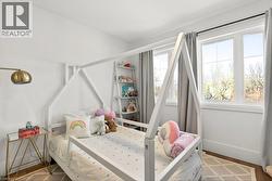 Bright room featuring two large windows, white walls, and wood-finish flooring - 