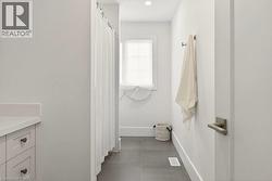 Bathroom featuring a white shower curtain, vanity with a white countertop and shaker-style cabinetry, a window with a white blind, and dark-toned floor tiles - 