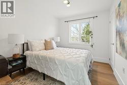 Bright room featuring light wood-finish flooring, white walls, and a white-trimmed window - 