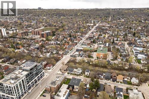 Expansive aerial perspective showcasing a residential and commercial area with tree-lined streets, varied architectural styles, and a mix of single-family homes and multi-story buildings - 128 Canada Street, Hamilton, ON - Outdoor With View