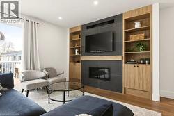 Living space featuring a tile-surround fireplace with a wood-finish mantel and integrated television mount - 