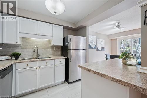 Kitchen featuring white cabinetry, a mosaic tile backsplash, and a double basin stainless steel sink with a gooseneck faucet - 365 Pioneer Drive Unit# 25, Kitchener, ON - Indoor Photo Showing Kitchen With Double Sink