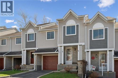 Townhouse exterior featuring light gray horizontal siding and dark gray shake accents - 365 Pioneer Drive Unit# 25, Kitchener, ON - Outdoor With Facade