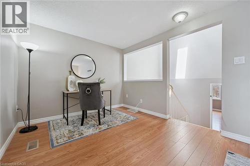 Open-concept space featuring wood-finish flooring, light grey wall paint, white baseboards, and a contemporary ceiling light fixture - 365 Pioneer Drive Unit# 25, Kitchener, ON - Indoor Photo Showing Other Room