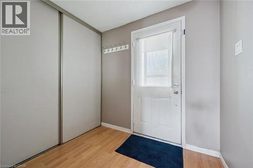 Entryway featuring wood-finish flooring, sliding closet doors, and a white paneled door with an integrated window blind - 365 Pioneer Drive Unit# 25, Kitchener, ON - Indoor Photo Showing Other Room