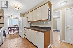 Kitchen featuring light-toned cabinetry with contrasting wood-finish bases, dark countertops, and tile flooring - 