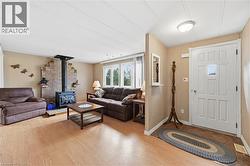Inviting living space featuring a wood-burning stove with a stone surround, light wood-finish flooring, and a large window providing natural light - 