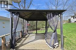 Screened gazebo with a dark metal frame and a slatted wood-finish deck - 