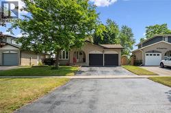 Brick exterior with a prominent mature tree and a two-car attached garage - 