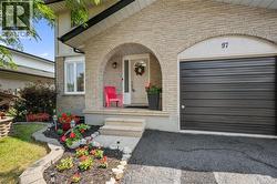 Brick facade entryway with an arched portico, featuring a dark panel garage door, white front door, and manicured front landscaping - 