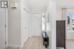 Entryway featuring light wood-finish flooring, white trim, and a frosted sidelight - 