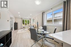 Open concept living and dining areas featuring wood-finish flooring, white crown molding, recessed lighting, and large windows - 