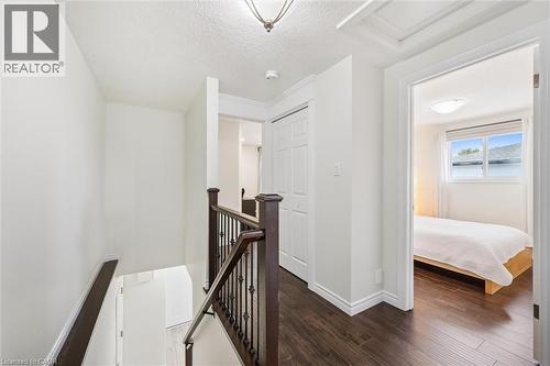 Upper-level landing featuring dark wood-finish flooring, white walls, and a staircase with dark wood handrails and black metal spindles - 97 Bechtel Drive, Kitchener, ON - Indoor Photo Showing Other Room