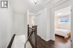 Upper-level landing featuring dark wood-finish flooring, white walls, and a staircase with dark wood handrails and black metal spindles - 
