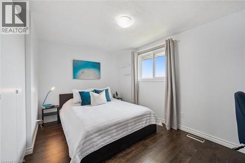 Bedroom featuring dark wood-finish flooring, a double-paned window, and a built-in closet with white doors - 97 Bechtel Drive, Kitchener, ON - Indoor Photo Showing Bedroom