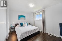 Bedroom featuring dark wood-finish flooring, a double-paned window, and a built-in closet with white doors - 