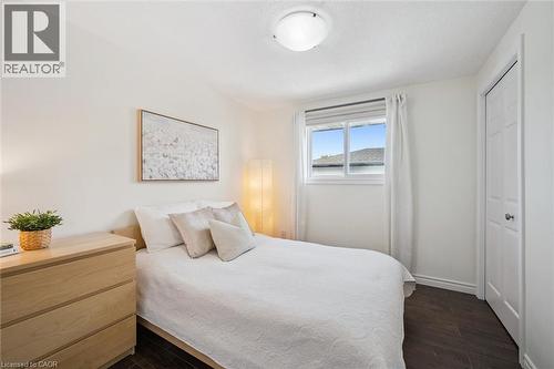 Bright room featuring dark wood-finish flooring, white walls, and a window with white blinds and curtains - 97 Bechtel Drive, Kitchener, ON - Indoor Photo Showing Bedroom