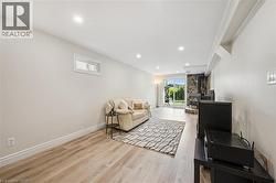 Spacious room featuring light-toned walls, wood-finish flooring, recessed lighting, and a window - 