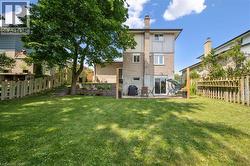 Spacious rear yard with a large grassy area, mature tree, and wood fencing - 