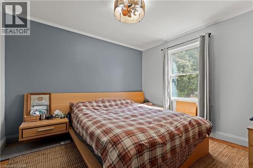 Bedroom featuring a single pane window with trim, crown molding, a built-in ceiling light fixture, wood-finish flooring, and a contrasting accent wall - 25 East 39Th Street, Hamilton, ON - Indoor Photo Showing Bedroom
