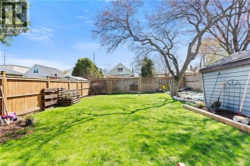 Spacious backyard featuring a manicured lawn, established mature tree, wood privacy fencing, and a detached shed with light blue siding - 25 East 39Th Street, Hamilton, ON - Outdoor