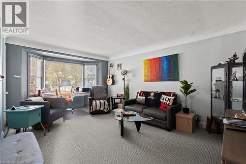 Living area with textured carpeting, a broad bay window, and light gray wall paint - 25 East 39Th Street, Hamilton, ON - Indoor Photo Showing Living Room