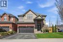 Contemporary two-story residence featuring a combination of brick and siding, a covered entry with stone accents, a two-car garage with decorative doors, a paved driveway, and a manicured front lawn - 47 Winners Way, Binbrook, ON  - Outdoor With Facade 