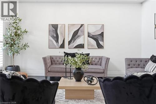 Light-filled living area featuring white walls, dark wood-finish flooring, and a large window with white plantation shutters - 47 Winners Way, Binbrook, ON - Indoor Photo Showing Living Room