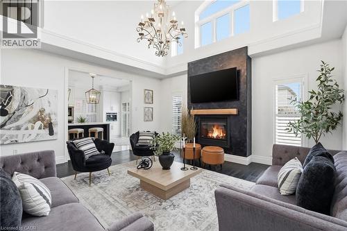 Spacious living area featuring a fireplace with a wood mantle, a textured dark stone surround, and an integrated television - 47 Winners Way, Binbrook, ON - Indoor Photo Showing Living Room With Fireplace