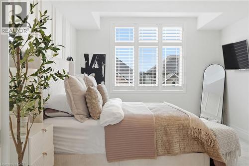 White interior with decorative wall paneling, a large window featuring white plantation shutters, and recessed ceiling lighting - 47 Winners Way, Binbrook, ON - Indoor Photo Showing Bedroom