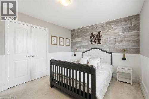 Interior space featuring a wood-finish accent wall, wainscoting, and carpet flooring - 47 Winners Way, Binbrook, ON - Indoor Photo Showing Bedroom