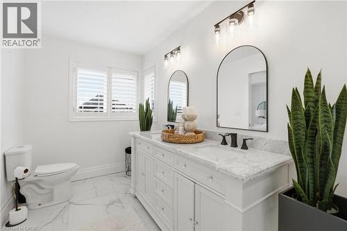 Bathroom featuring a white dual vanity with a marble-finish countertop, matte black fixtures, and two arched mirrors - 47 Winners Way, Binbrook, ON - Indoor Photo Showing Bathroom