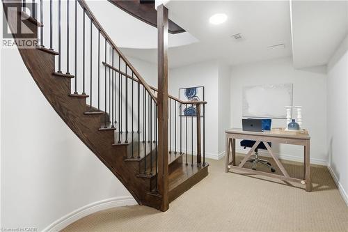 Curved wood staircase with black metal balusters - 47 Winners Way, Binbrook, ON - Indoor Photo Showing Other Room