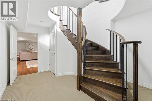 Curved hardwood staircase with wrought iron balusters and a dark wood handrail - 47 Winners Way, Binbrook, ON - Indoor Photo Showing Other Room