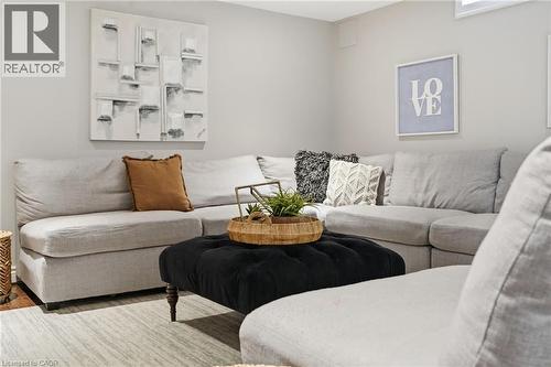 Spacious living area featuring light gray walls, a large sectional sofa, and a black tufted ottoman - 47 Winners Way, Binbrook, ON - Indoor Photo Showing Living Room