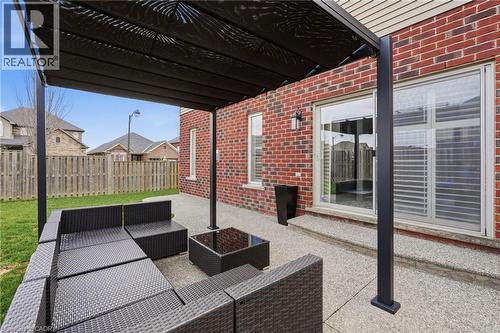 Covered patio featuring a solid brick exterior, sliding glass doors, a transom window, and a stone-finish patio surface - 47 Winners Way, Binbrook, ON - Outdoor With Exterior