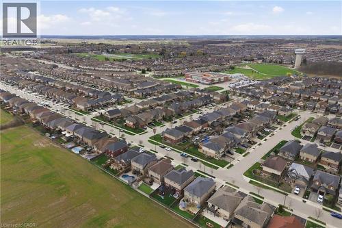 Aerial perspective showcasing a residential community with diverse single-family homes, manicured lawns, paved streets, and a green space in the distance - 47 Winners Way, Binbrook, ON - Outdoor With View