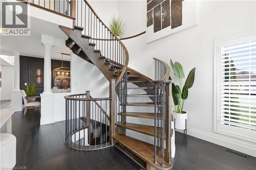 Grand spiral staircase with dark wood-finish treads and wrought iron balusters - 47 Winners Way, Binbrook, ON - Indoor Photo Showing Other Room