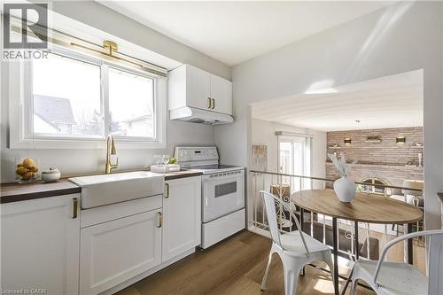 Modern kitchen featuring white cabinetry, wood-finish countertops, and a farmhouse sink with a gold-tone faucet - 217 Lawnhurst Court, Hamilton, ON - Indoor