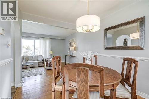 Light-filled dining area featuring wood-finish flooring, a contemporary drum pendant light, and a decorative wall mirror - 217 Lawnhurst Court, Hamilton, ON - Indoor Photo Showing Dining Room