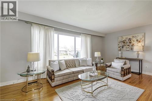 Living room featuring large windows, wood-finish flooring, and light-toned wall paint - 217 Lawnhurst Court, Hamilton, ON - Indoor Photo Showing Living Room