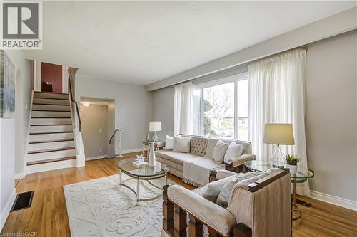 Bright living area featuring wood-finish flooring and a staircase with white risers and wood treads - 217 Lawnhurst Court, Hamilton, ON - Indoor Photo Showing Living Room
