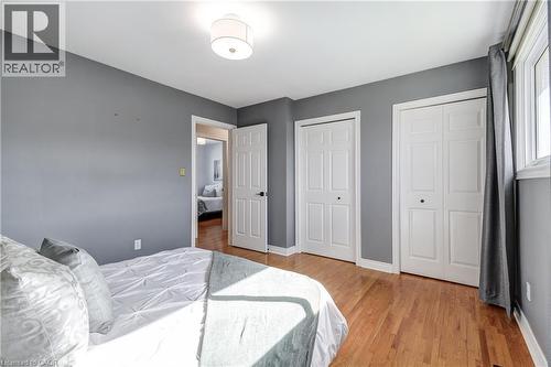 Bedroom featuring wood-finish flooring, two bi-fold closets, a window with natural light, and a flush mount ceiling fixture - 217 Lawnhurst Court, Hamilton, ON - Indoor Photo Showing Bedroom