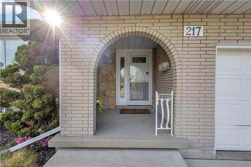 Brick exterior featuring an arched entryway, concrete porch, and white decorative railing - 217 Lawnhurst Court, Hamilton, ON - Outdoor With Exterior