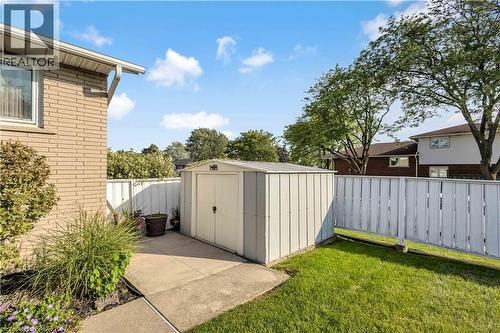 Backyard featuring a detached storage shed, concrete pad, green lawn, and white privacy fencing - 217 Lawnhurst Court, Hamilton, ON - Outdoor