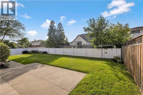 Expansive backyard featuring a concrete patio, a manicured lawn, a white privacy fence, and mature trees - 217 Lawnhurst Court, Hamilton, ON - Outdoor With Backyard